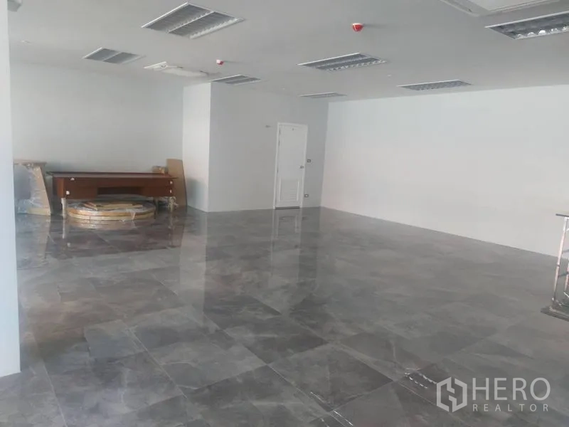 零售空间 出租 - 宽敞空铺，抛光地砖、白色墙面与天花灯，后方有房门。