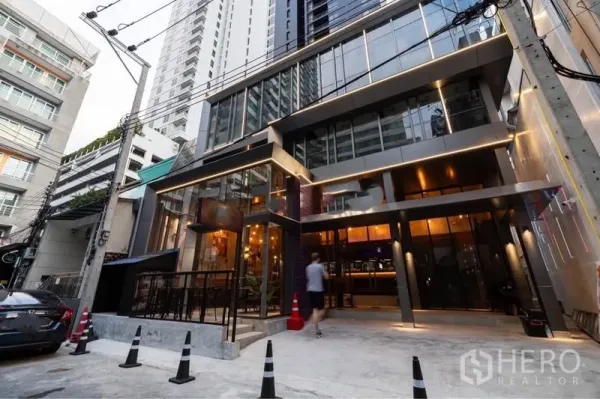 Retail Space for rent in Watthana, Bangkok - Modern glass-front commercial building exterior with warm lighting and direct street access in a lively urban lane.
