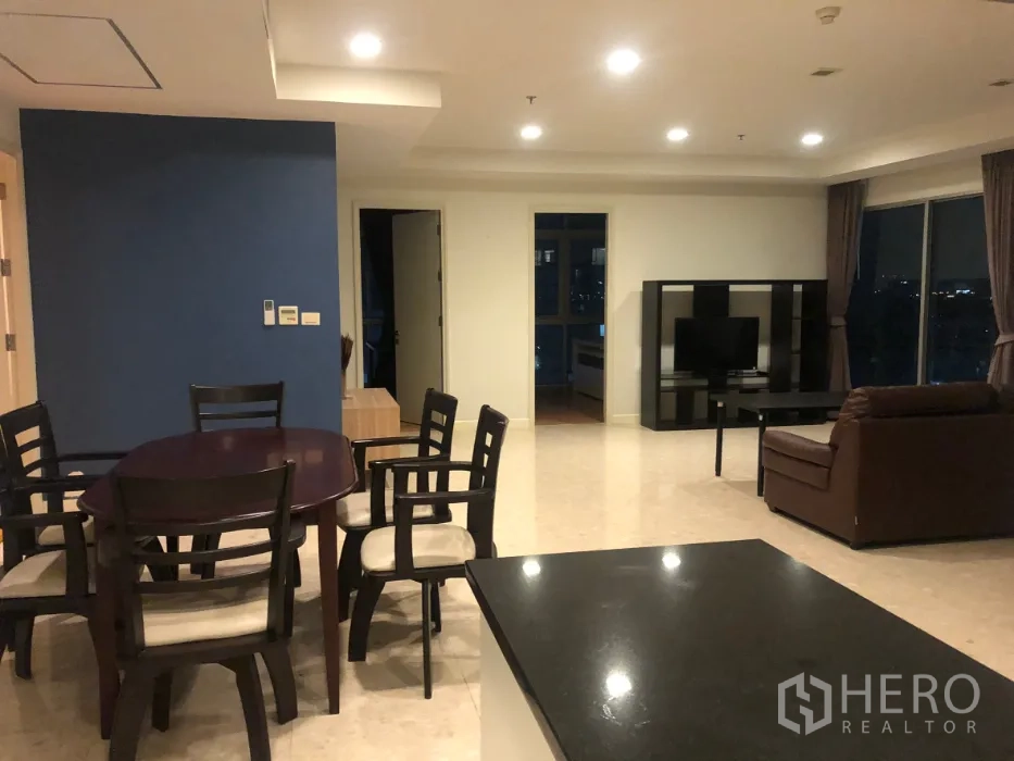 Condominium for sale in Khlong Toei, Bangkok - Open-plan living and dining area with marble floors, sofa, TV and a dining table.