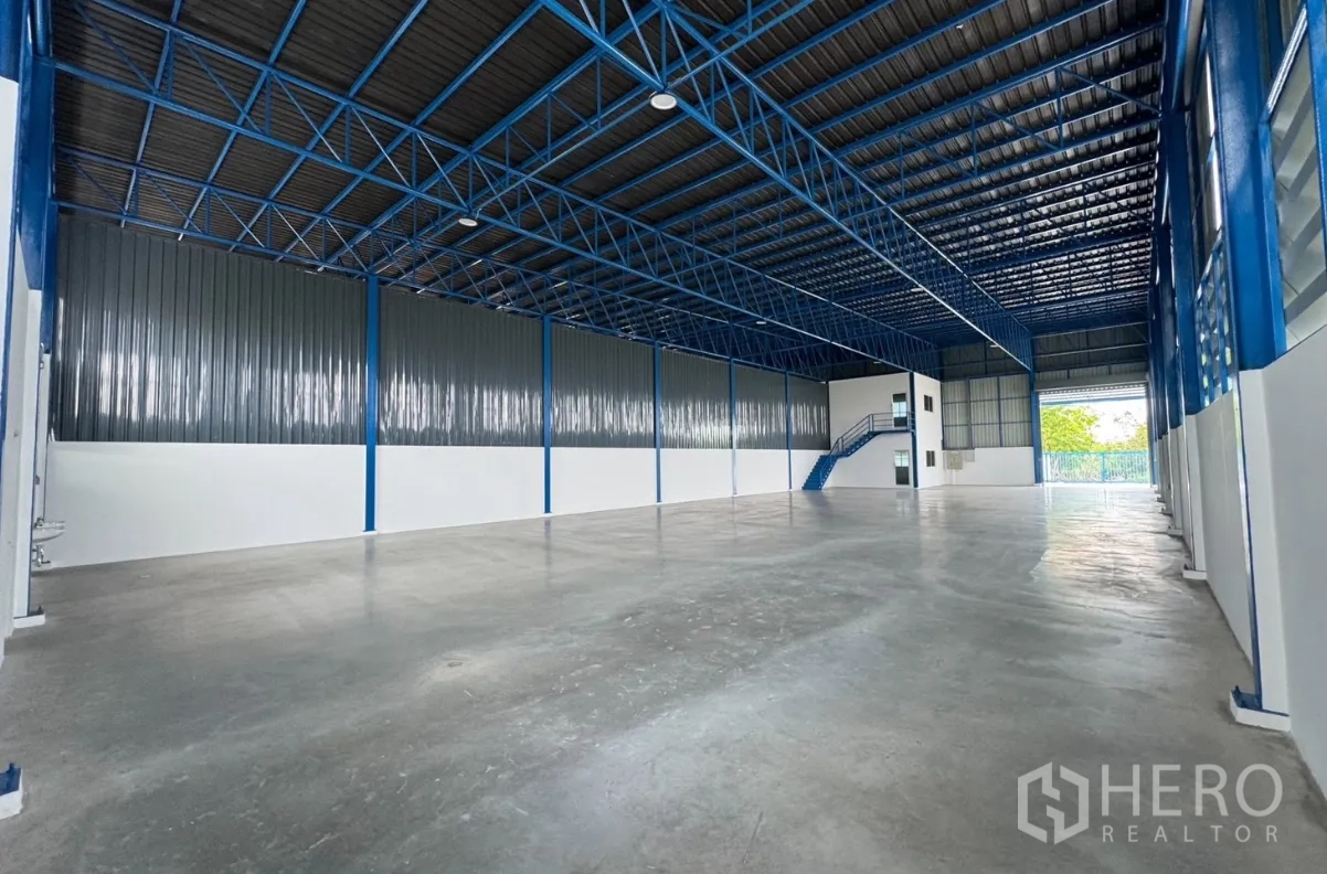 Warehouse for rent in Khlong Luang, Pathum Thani - Spacious warehouse interior with high steel truss roof, concrete floor, and a two-storey office room.