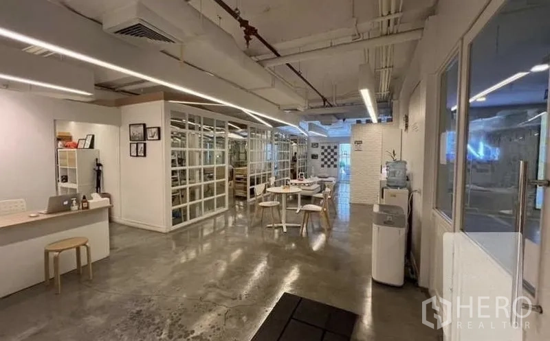 Retail Space for rent - Front workspace of the unit with a counter, round table, and glass partition walls.