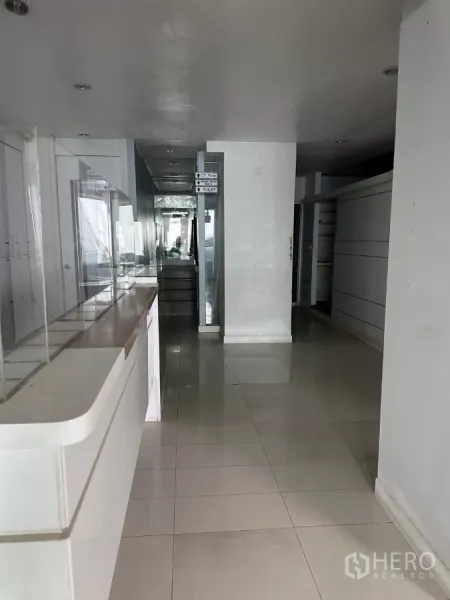Shophouse for sale in Watthana, Bangkok - Long corridor with built-in counter and recessed ceiling lights on the first floor.