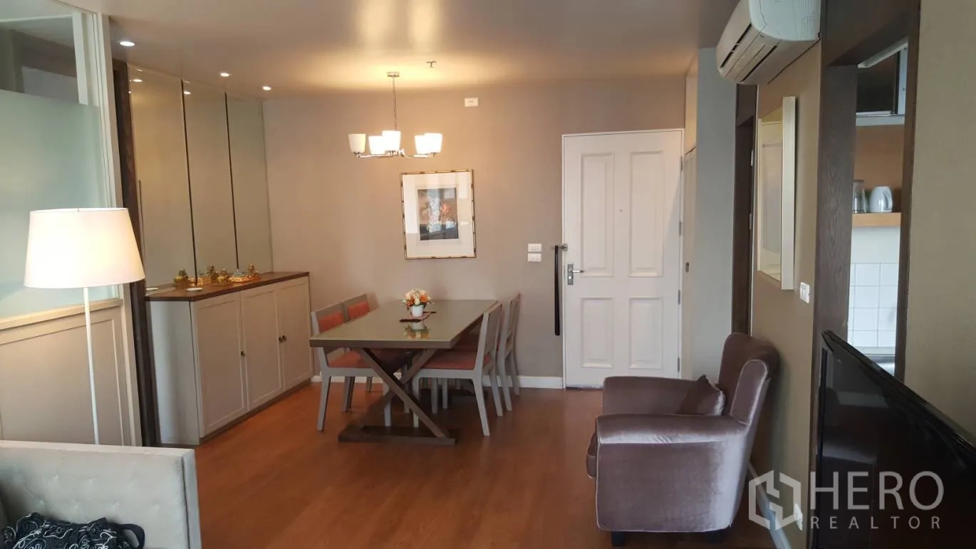 Condominium for rent in Khlong Toei, Bangkok - Dining area with four-seat table, pendant lighting, built-in cabinets and the entry door.
