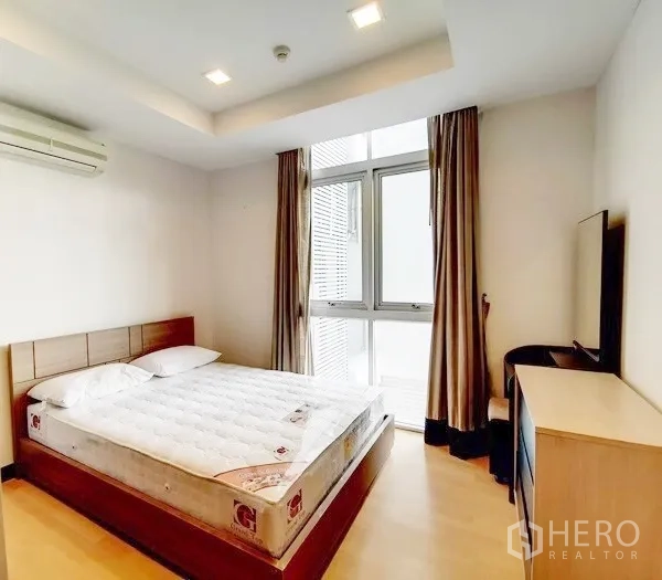 Condominium for rent in Khlong Toei, Bangkok - Bright third bedroom with double bed, big window, curtains and a TV console.