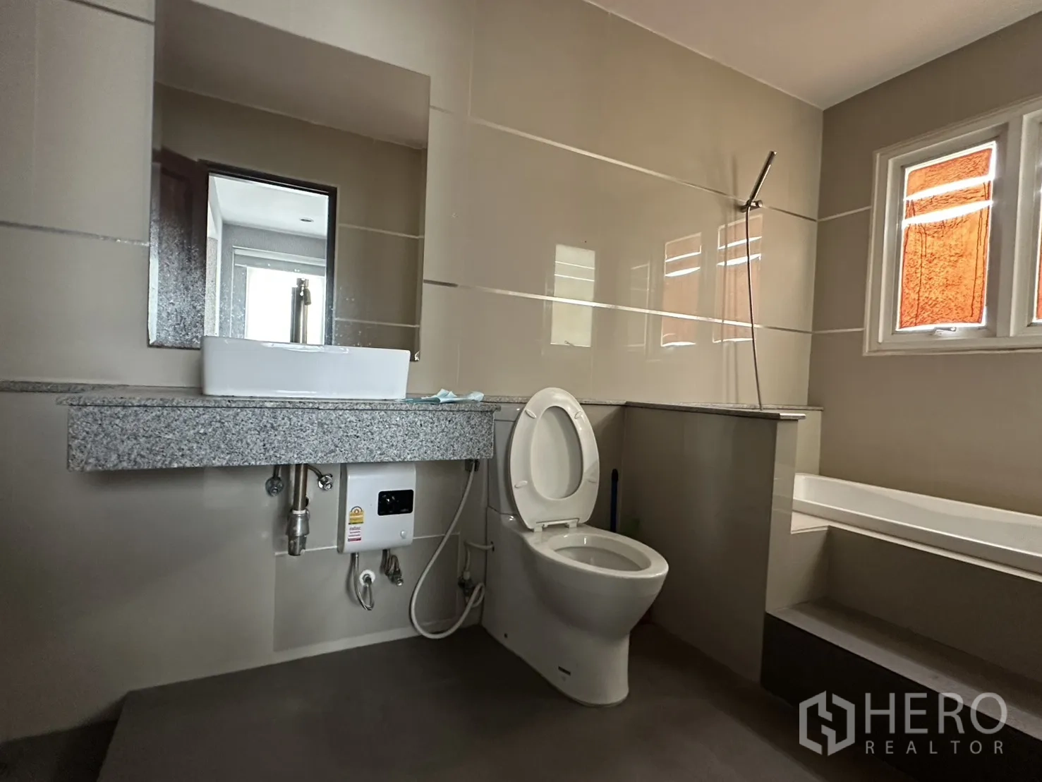 Home Office for rent in Watthana, Bangkok - Bathroom with granite countertop, toilet and a raised bathtub platform below windows.