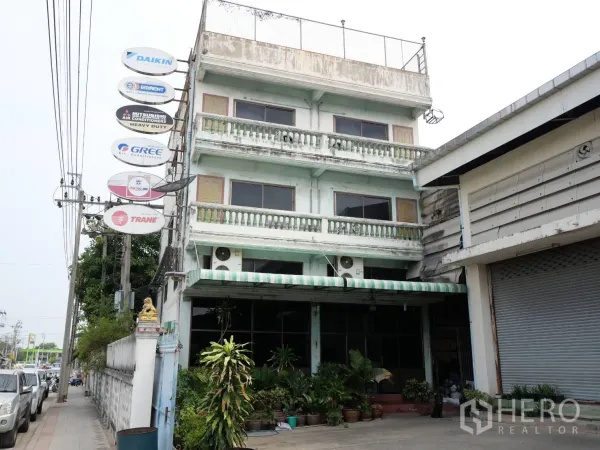 Factory for rent or sale in Bang Khun Thian, Bangkok - Front facade of the 3.5-storey commercial office building with awning and roller shutter beside the factory.
