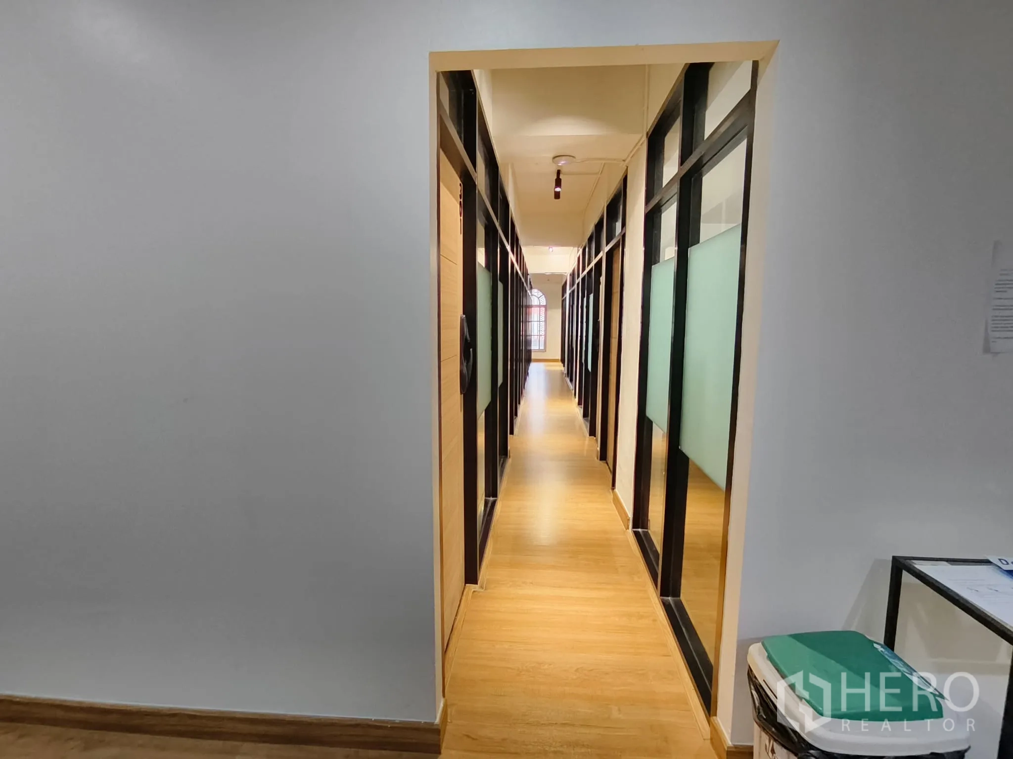 Shophouse for rent in Watthana, Bangkok - Hallway lined with glass-partition private offices and frosted panels.