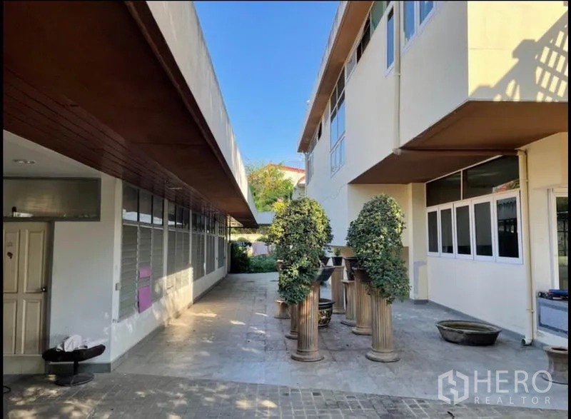 Detached House for rent in Khlong Toei, Bangkok - Side courtyard between two building wings featuring windows and ornamental topiary.