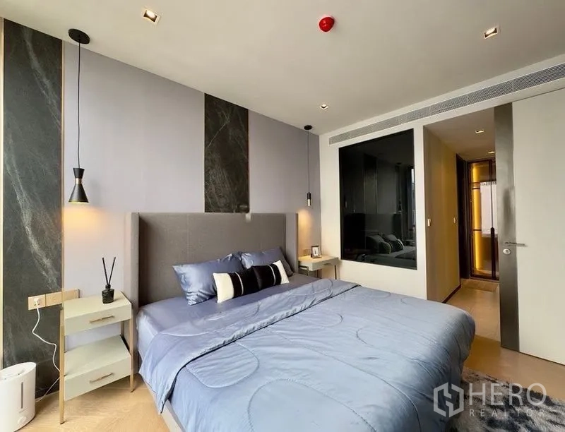 Condominium for rent or sale in Watthana, Bangkok - Modern bedroom with upholstered headboard, pendant lights, and bedside tables.