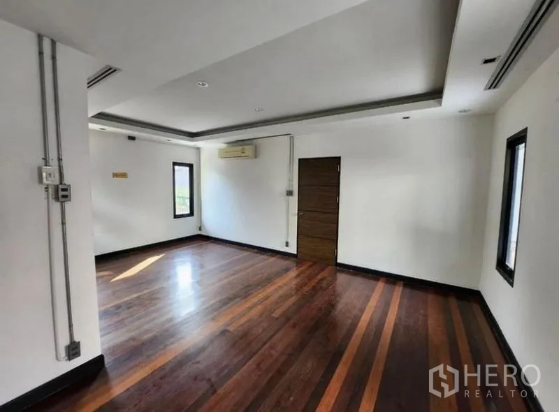 สำนักงานที่บ้าน ให้เช่าในLat Phrao, Bangkok - ห้องทำงานกว้าง พื้นไม้ขัดเงา ผนังสีขาว และไฟดาวน์ไลต์ พร้อมประตูทางเดิน