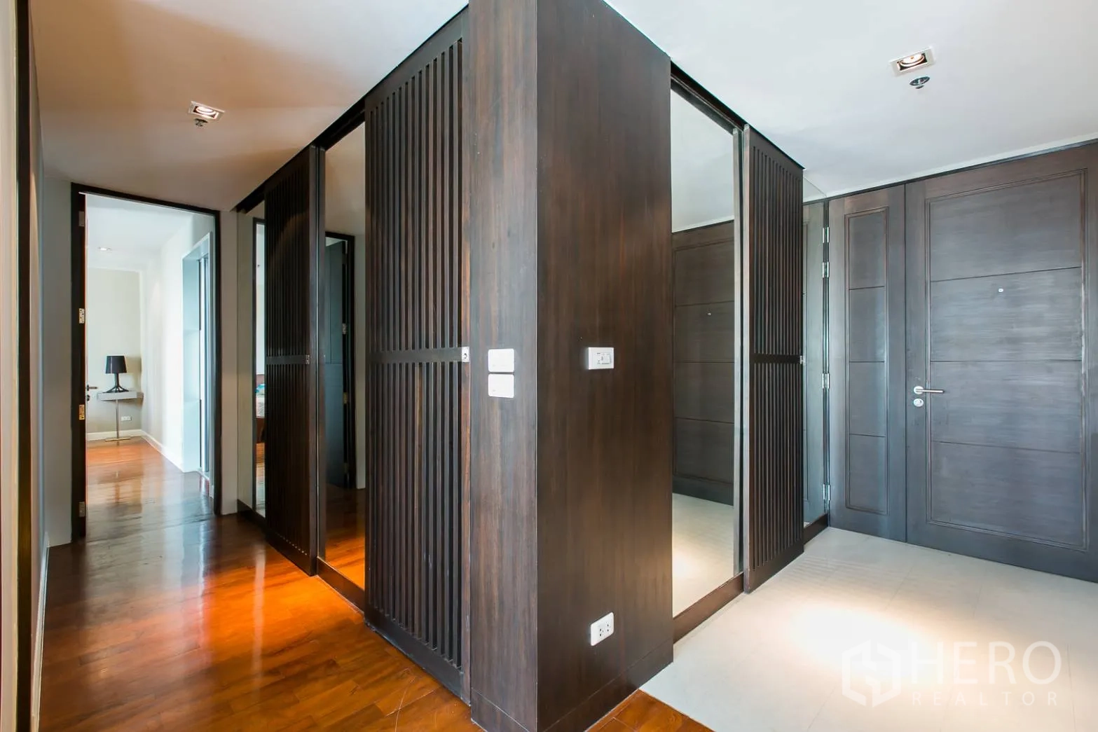 Condominium for rent or sale in Khlong Toei, Bangkok - Hallway with dark wood paneled closets, mirrors and hardwood flooring.