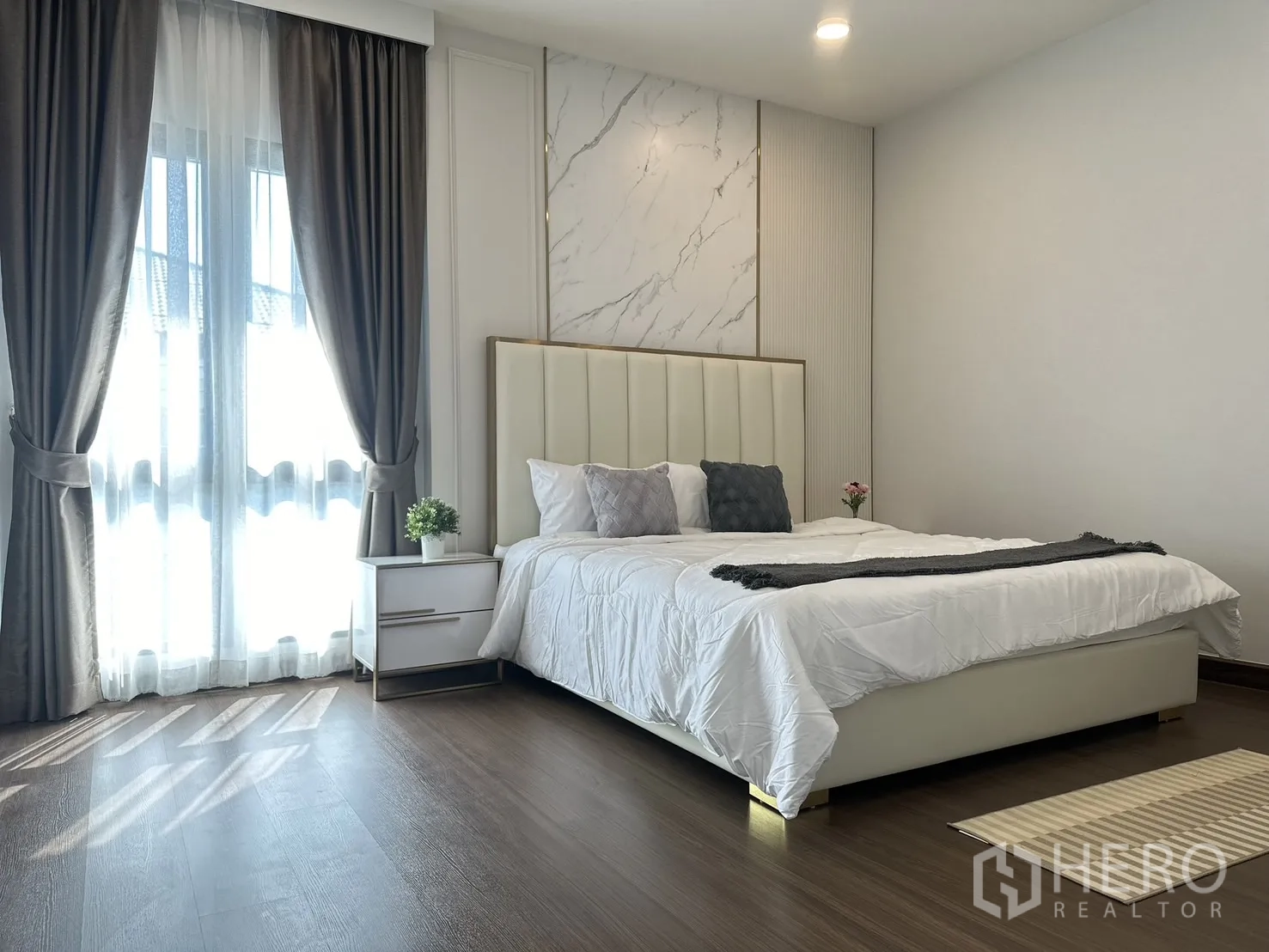Detached House for rent or sale - Master bedroom with paneled marble feature wall, tall headboard, balcony doors with drapes and wood floors.