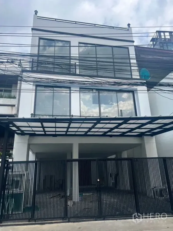 Home Office for rent or sale in Watthana, Bangkok - Street view of the home office with black metal fence and glass-fronted exterior.