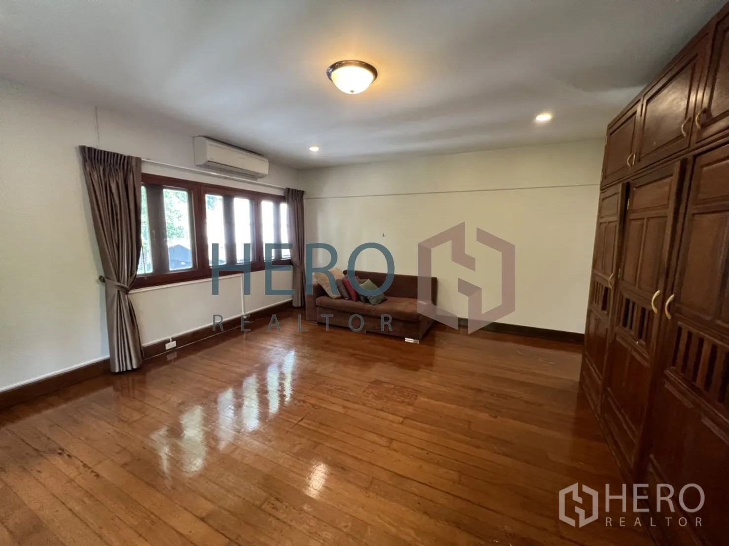 Detached House for rent in Watthana, Bangkok - Spacious bedroom with wooden flooring and full-height wardrobes.