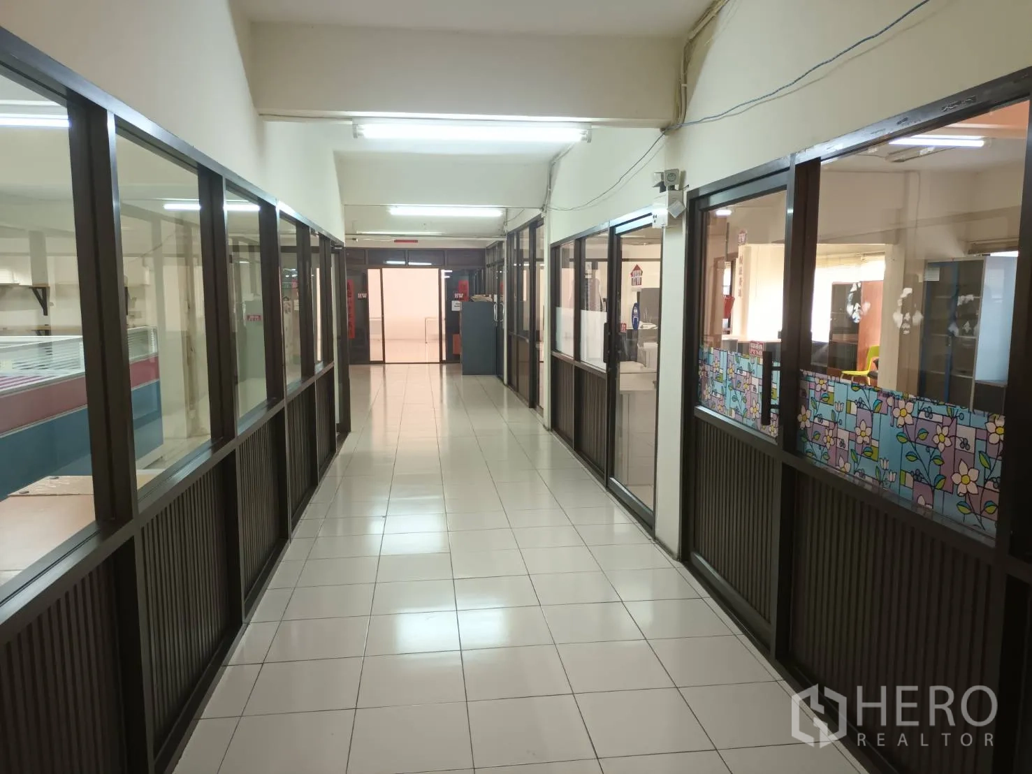 Warehouse for rent in Bang Phli, Samut Prakan - Corridor with glass-partitioned offices on both sides, tiled floor and fluorescent lighting.