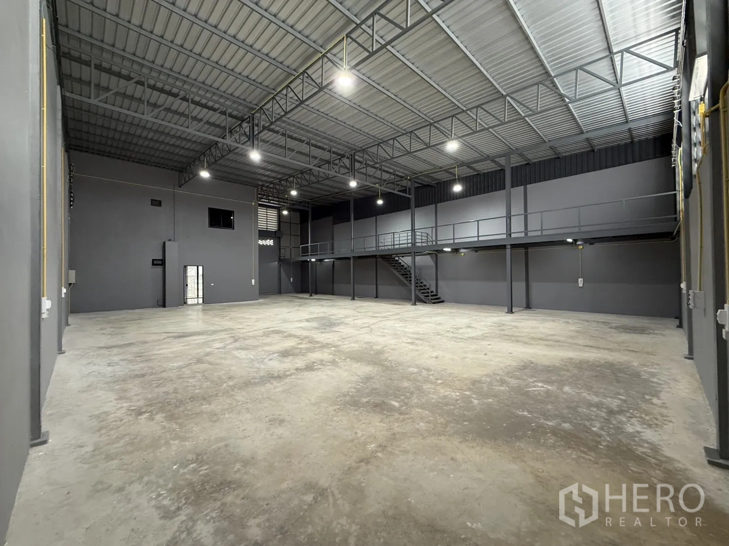 Warehouse for rent in Lam Luk Ka, Pathum Thani - Wide-span warehouse with mezzanine platform and stair access.