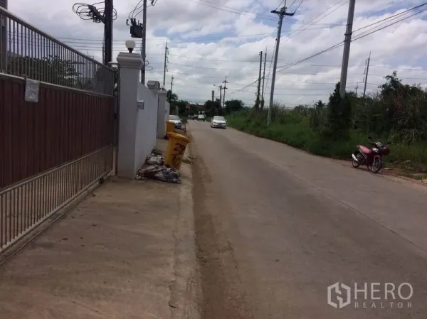 工厂 出租或出售在Mueang Samut Sakhon, Samut Sakhon - 物业大门外的支路景观，沿线电杆与稀疏车流。