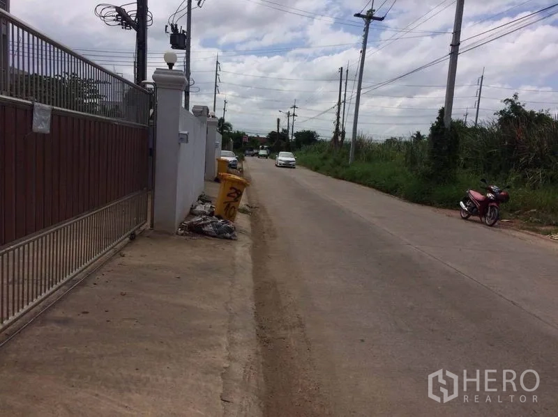 工厂 出租或出售在Mueang Samut Sakhon, Samut Sakhon - 物业大门外的支路景观，沿线电杆与稀疏车流。