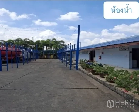 Warehouse for rent in Mueang Pathum Thani, Pathum Thani - Outdoor walkway leading to a restroom block beside the yard with plants.