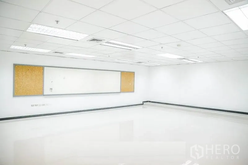 Office Space for rent in Bang Na, Bangkok - Bright open-plan office with white tiled floors, drop ceiling lighting, and a long whiteboard with cork boards.