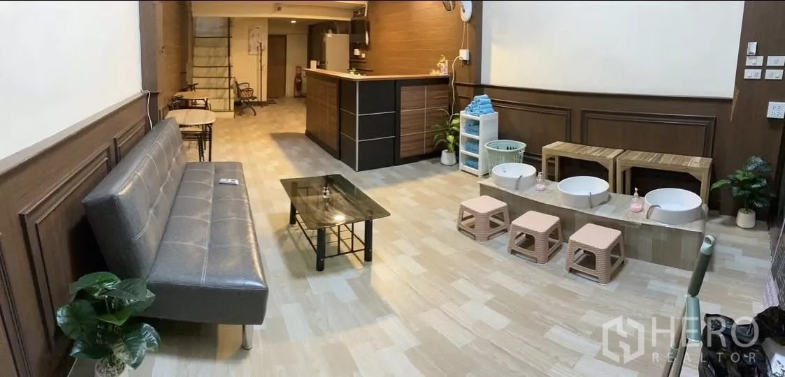 Shophouse for rent in Watthana, Bangkok - Open‑plan lounge with sofa, reception counter and stairs in a spa‑style shophouse.