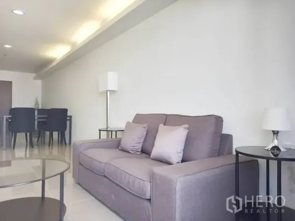 Condominium for rent in Khlong Toei, Bangkok - Cozy gray sofa with side tables and a floor lamp in a minimalist living space.