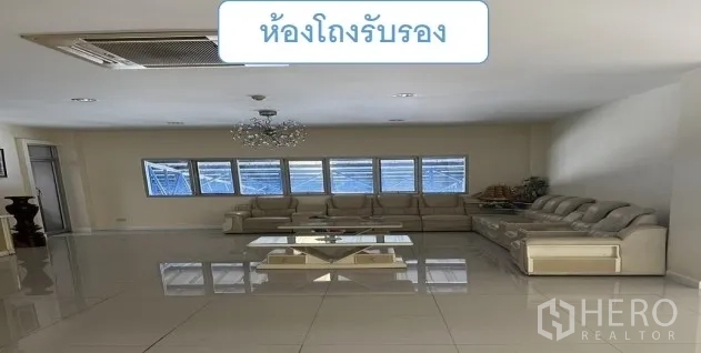 Warehouse for rent in Mueang Pathum Thani, Pathum Thani - Lounge reception area with an L-shaped sofa, chandelier and a wall of windows.