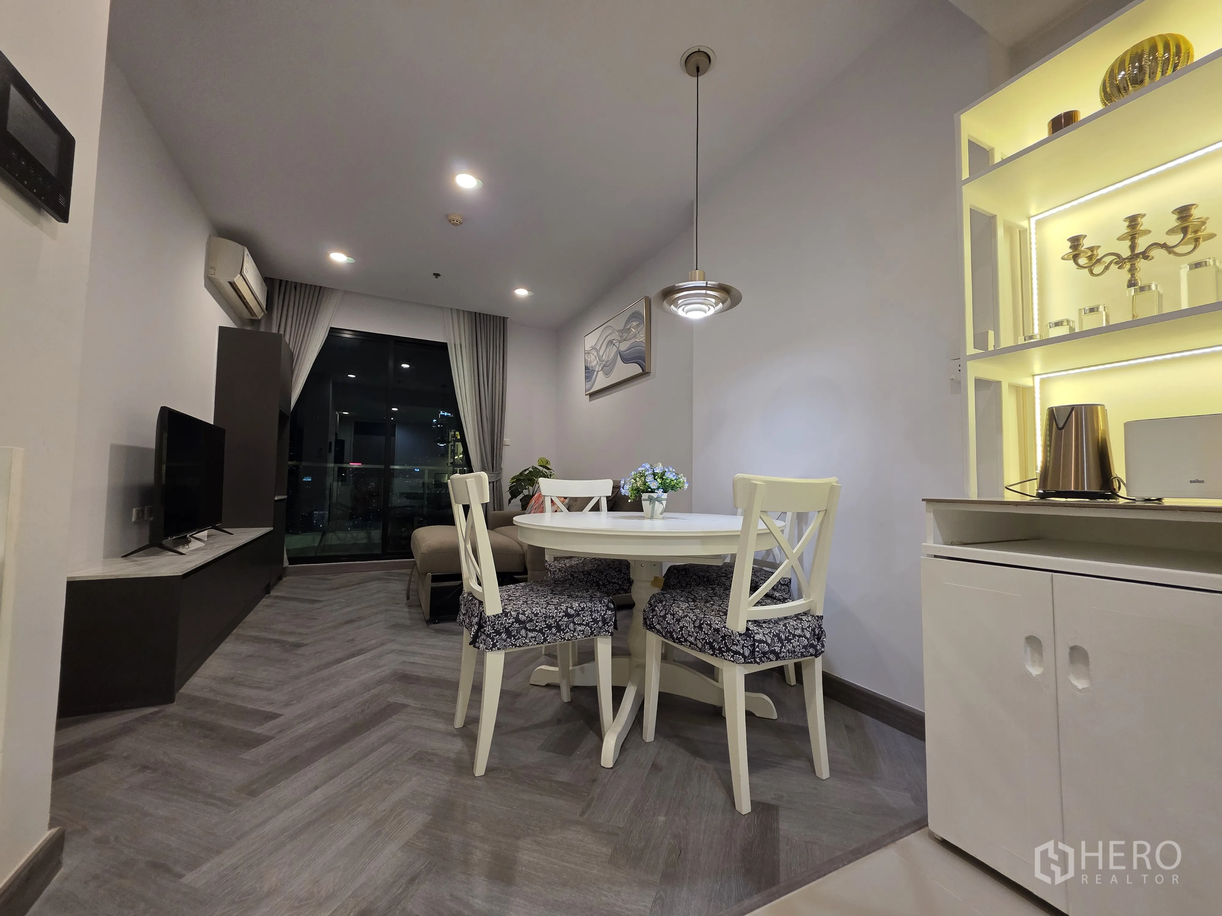 Condominium for rent in Bang Kapi, Bangkok - Round dining table with three chairs beside sleek kitchen cabinetry.