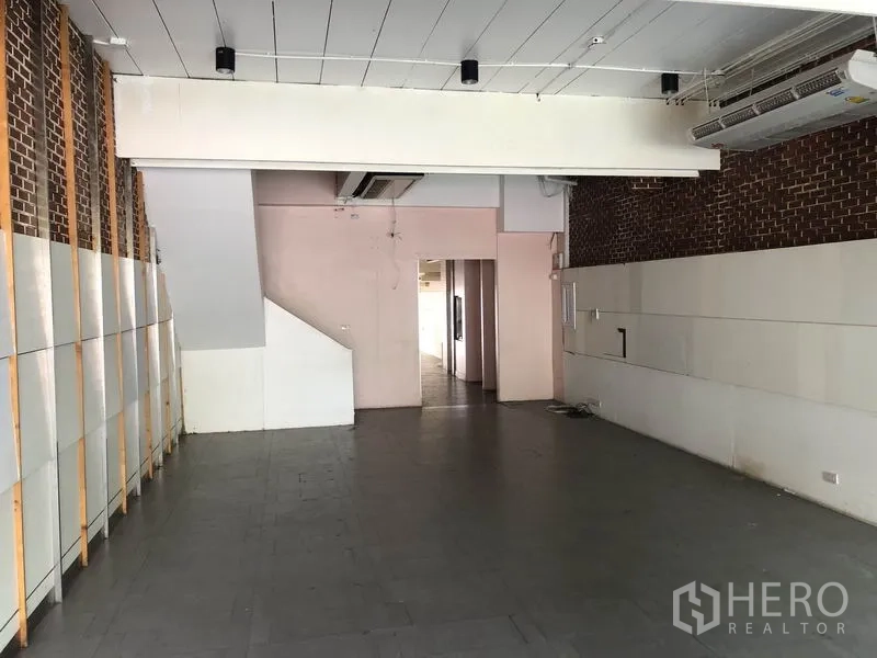 Home Office for rent or sale in Huai Khwang, Bangkok - Ground-floor space showing brick feature wall, tiled flooring and doorway to the rear.