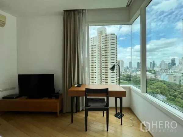 Condominium for rent in Khlong Toei, Bangkok - Corner work desk by panoramic windows showcasing Bangkok skyline and greenery.