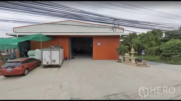 Warehouse for rent in Bang Kapi, Bangkok - Front facade of the red warehouse featuring a wide entrance and a concrete loading forecourt.