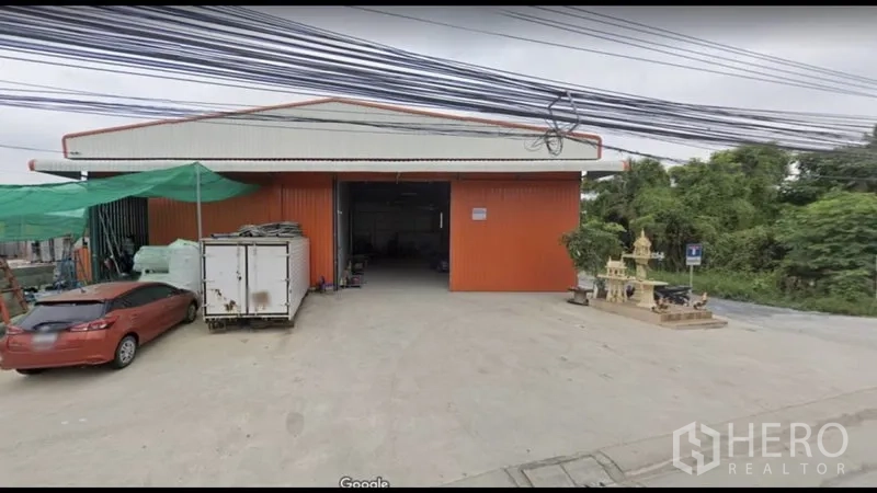 Warehouse for rent in Bang Kapi, Bangkok - Front facade of the red warehouse featuring a wide entrance and a concrete loading forecourt.