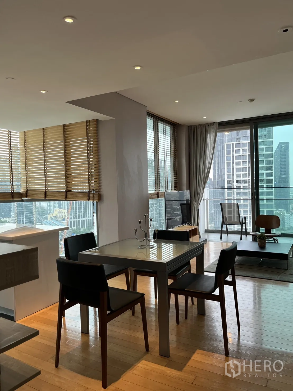 Condominium for rent in Watthana, Bangkok - Open-plan living and dining area with wood floors and city views through wide windows.
