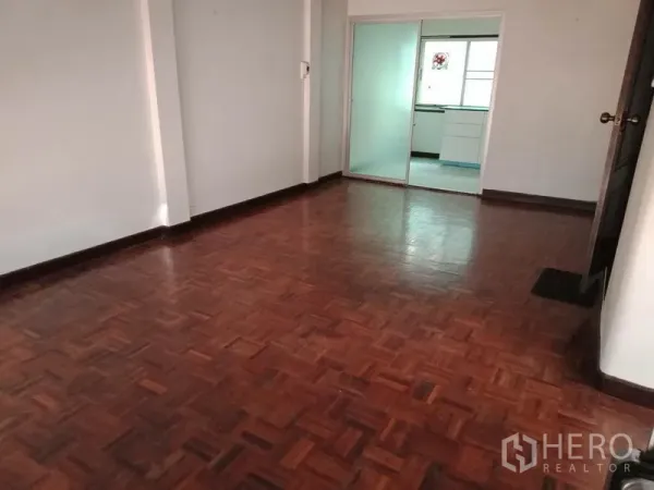 Home Office for rent in Khlong Toei, Bangkok - Spacious room with parquet floor leading to a glass-partitioned kitchen.