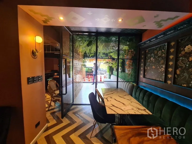 Retail Space for rent in Bang Rak, Bangkok - Indoor seating by a glass entry with marble table, green banquette and geometric flooring.
