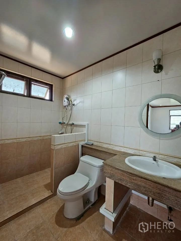 Home Office for rent in Wang Thonglang, Bangkok - Beige tiled bathroom with walk‑in shower, toilet and wide countertop basin.
