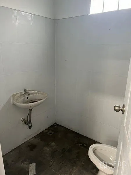 Warehouse for rent in Khlong Sam Wa, Bangkok - Simple warehouse restroom with white tiled walls, a wall-mounted sink and toilet.