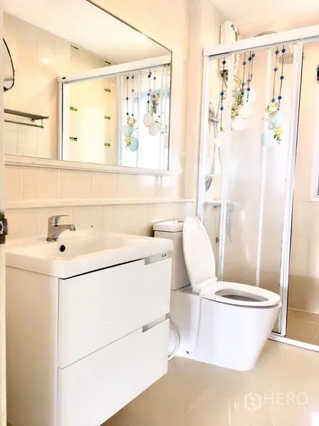 Townhouse for rent in Prawet, Bangkok - A clean bathroom with a vanity, toilet and glass-enclosed shower.