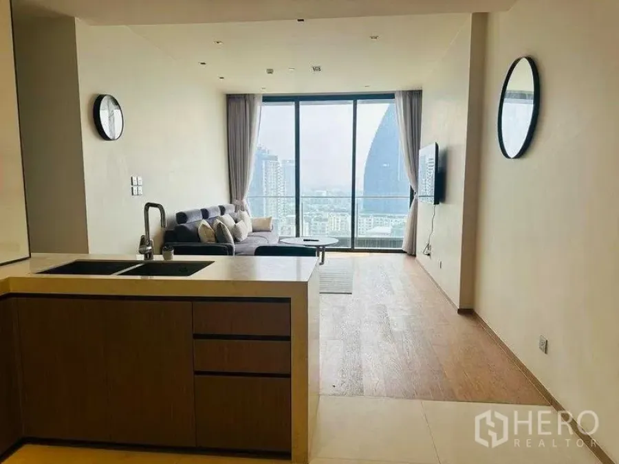 Condominium for rent in Khlong Toei, Bangkok - Open-plan living room and kitchen with floor-to-ceiling windows and Bangkok skyline view.