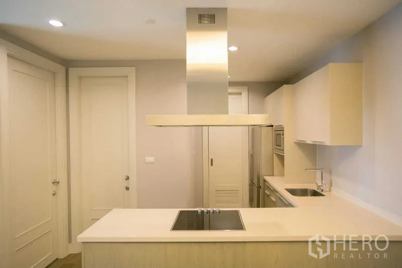Condominium for rent or sale in Pathum Wan, Bangkok - Compact modern kitchen with island cooktop, range hood and built-in appliances.