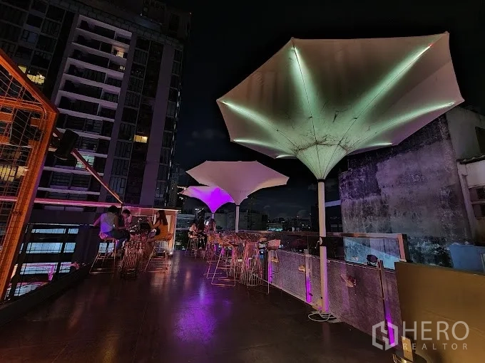 Retail Space for rent - Rooftop seating with sculptural umbrella canopies, purple lighting and skyline backdrop.