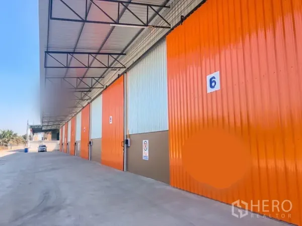 Warehouse for rent in Khlong Luang, Pathum Thani - Numbered warehouse bays with bright orange panels and ample truck access in front.