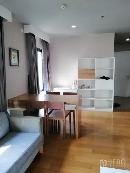 Condominium for rent in Watthana, Bangkok - Open-plan dining area with table and shelving in a sunlit corner