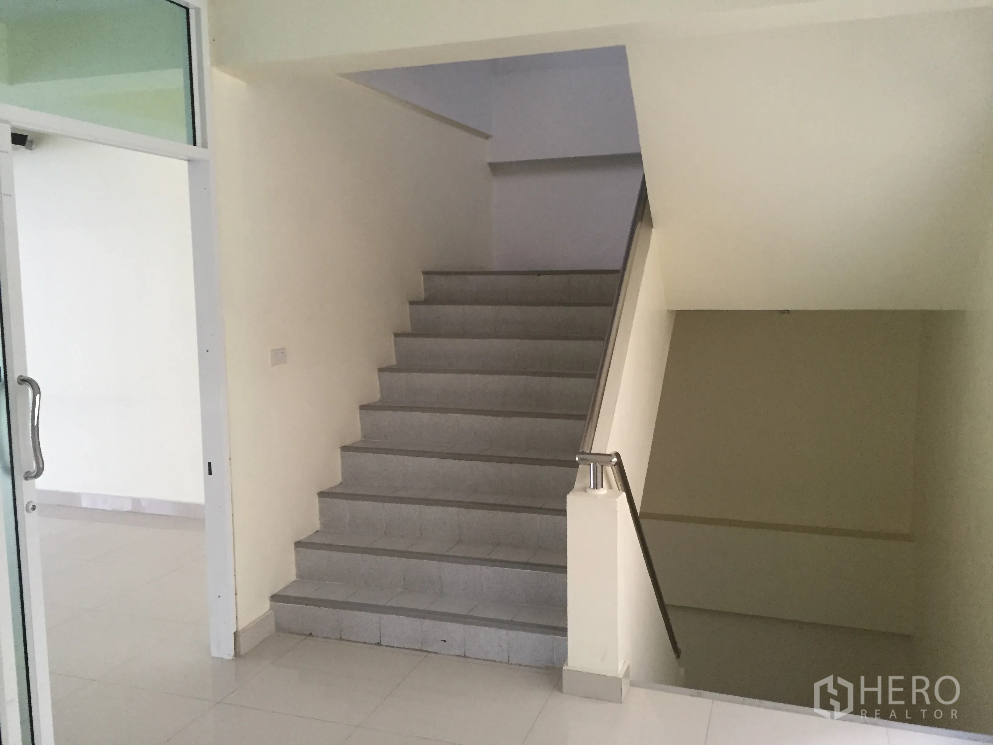 Office Space for rent in Bang Kapi, Bangkok - Interior stairwell with stainless handrail next to a glass door and bright corridor.