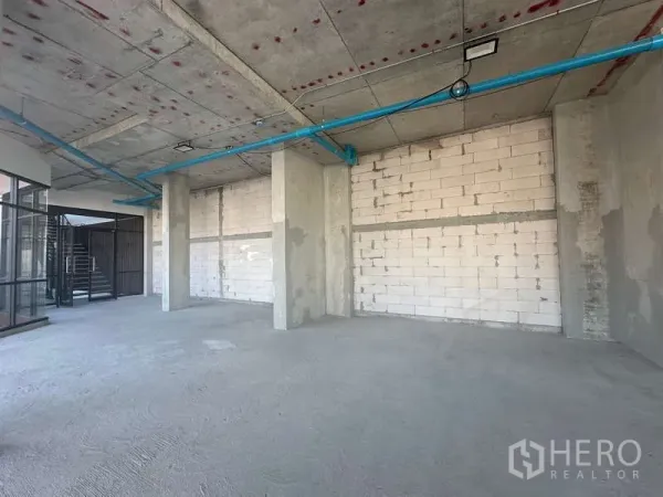 Retail Space for rent in Phra Khanong, Bangkok - Open-plan shell retail unit with concrete pillars, block walls, and exposed services next to a stair lobby.