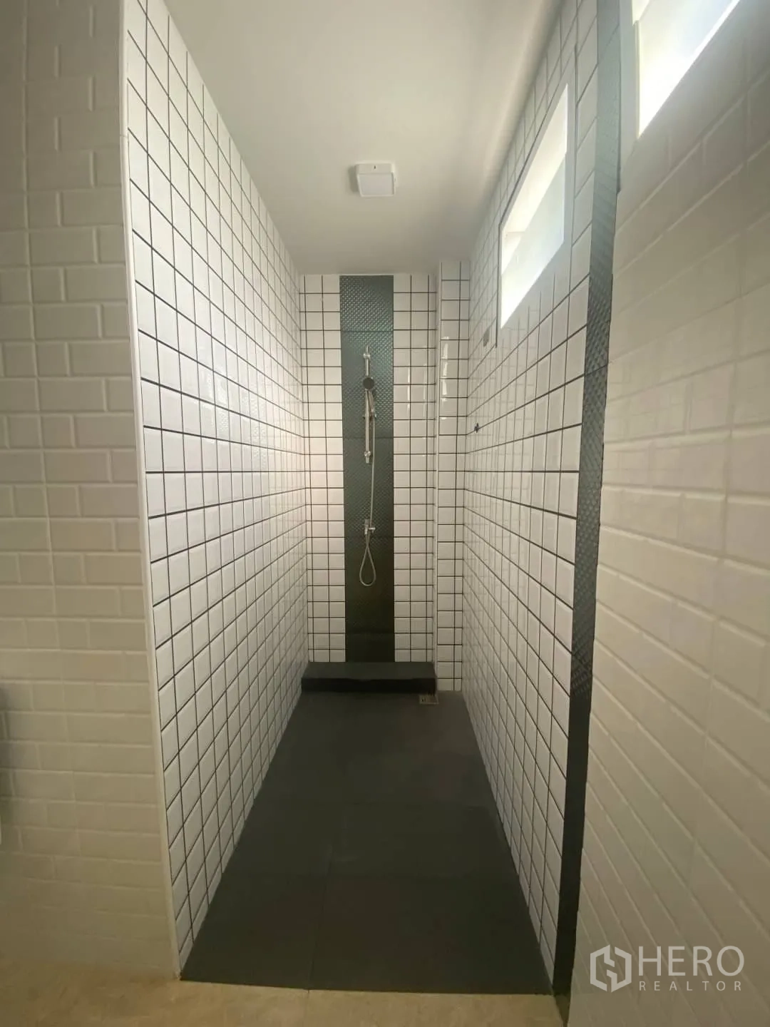 Home Office for sale - Long walk-in shower lined with white tiles and a dark accent column.