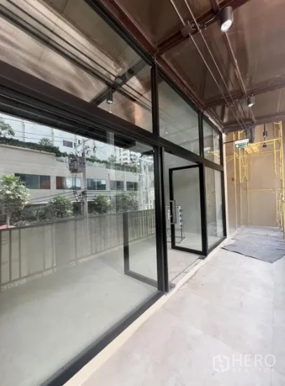 Retail Space for rent in Khlong Toei, Bangkok - Corner glass-front retail unit with floor-to-ceiling windows and a covered walkway.