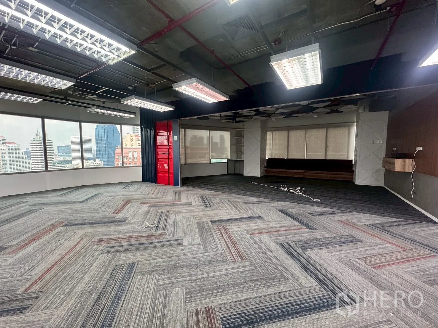Office Space for rent in Watthana, Bangkok - Corner office area with large windows showing city skyline views and a red feature wall.