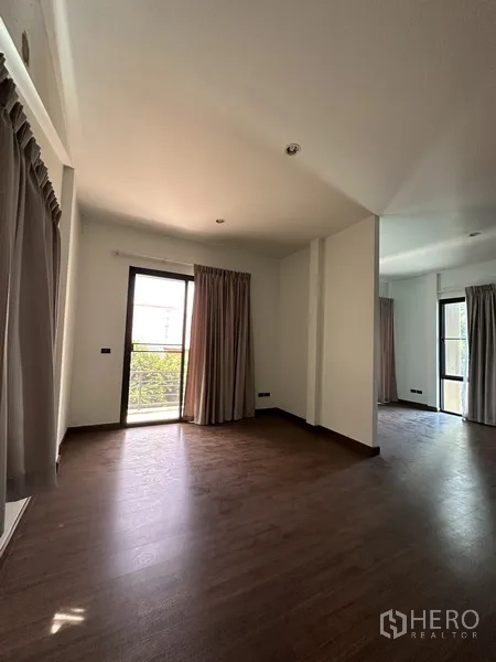 Home Office for rent in Watthana, Bangkok - Sunlit bedroom with wood floors and balcony doors.