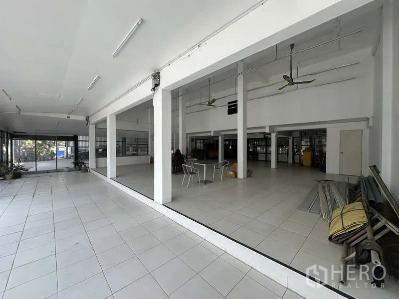 货栈 出租在Pak Kret, Nonthaburi - 开放式展厅空间，白色立柱、吊扇与瓷砖地面。